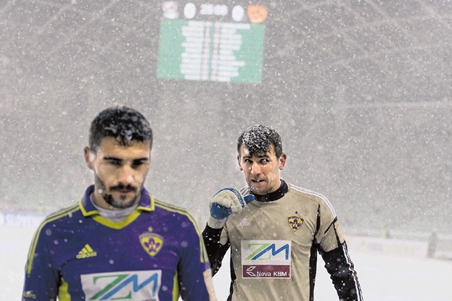 Nogometaši  (na fotografiji člana Maribora Aleksander Rajčević in Jasmin Handanović) upajo, da jih sneg danes v Stožicah ne...