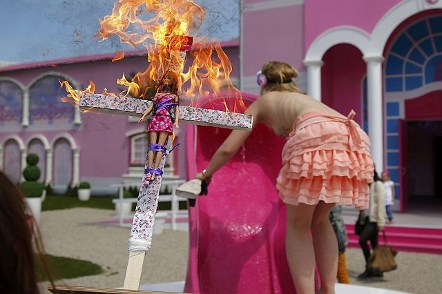 Aktivistka skupine Femen se vzpenja na »delovno mesto«, v ospredju njen rekvizit (foto: Reuters) 