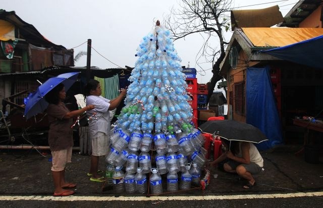 Žrtve filipinskega tajfuna Haiyan okrašujejo svojo improvizirano smrečico z praznimi plastenkami in pločevinkami. (Foto:...