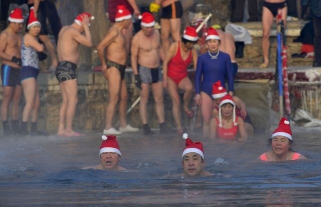 Na Kitajskem se v pričakovanju božiča ljudje z božičkovimi kapami na glavah kopajo v delno zamrznjenem jezeru. (Foto:...