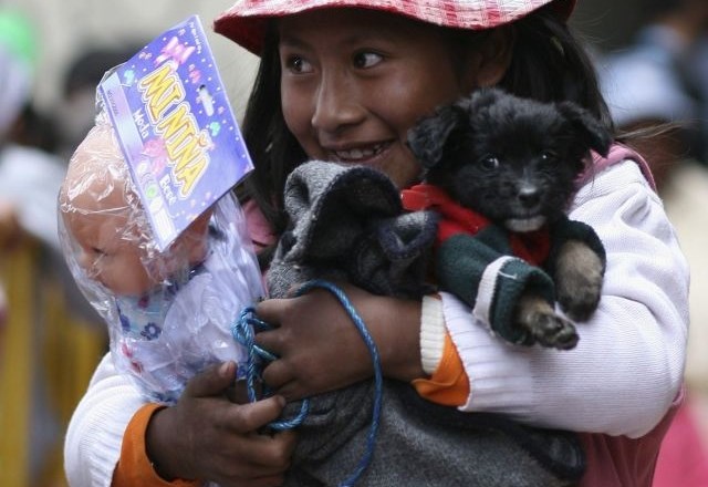 Deklica iz Bolivije v roki drži psička in igračo, ki jo je ob božiču dobila od katoliške organizacije Carros de Fuego, ki...
