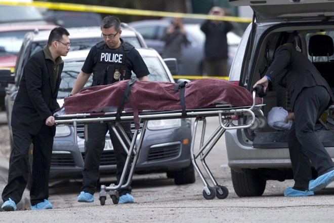 Police remove a body from the scene of a multiple fatal stabbing in northwest Calgary, Alberta, Tuesday, April 15, 2014....