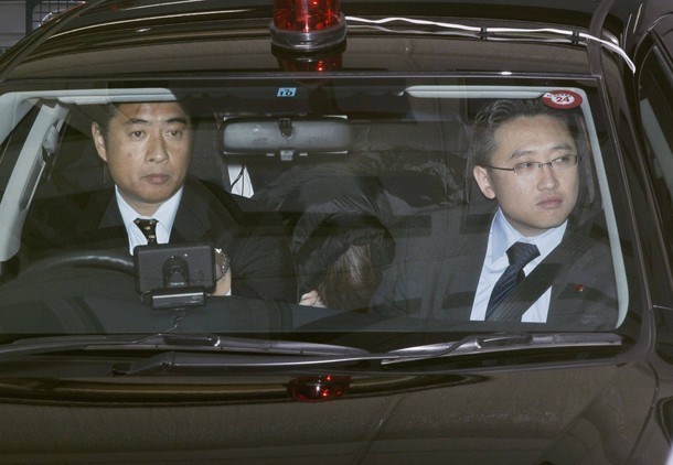 Makoto Hirata (ki se skriva v sredini) v policijskem avtomobilu.