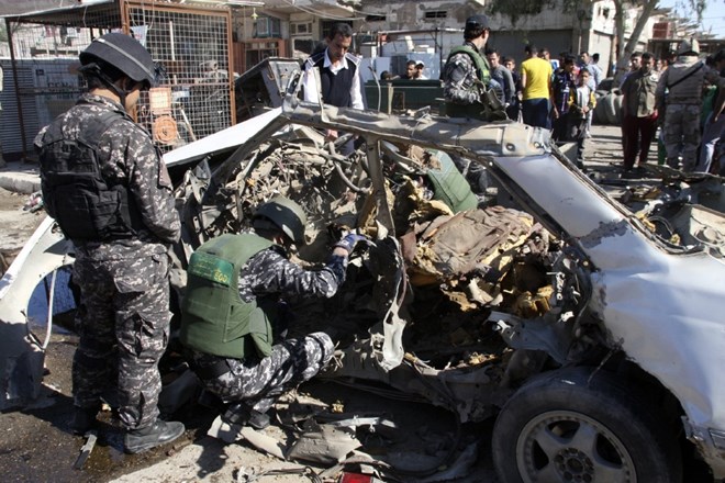 Iraški policisti preiskujejo prizorišče eksplozije avtomobila bombe.     