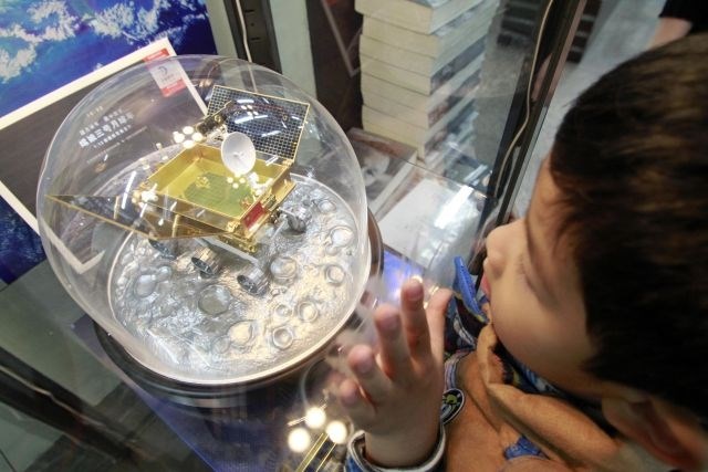 Deček si ogleduje model kitajskega vesoljskega plovila, ki je danes pristalo na luni (Foto: Reuters) 