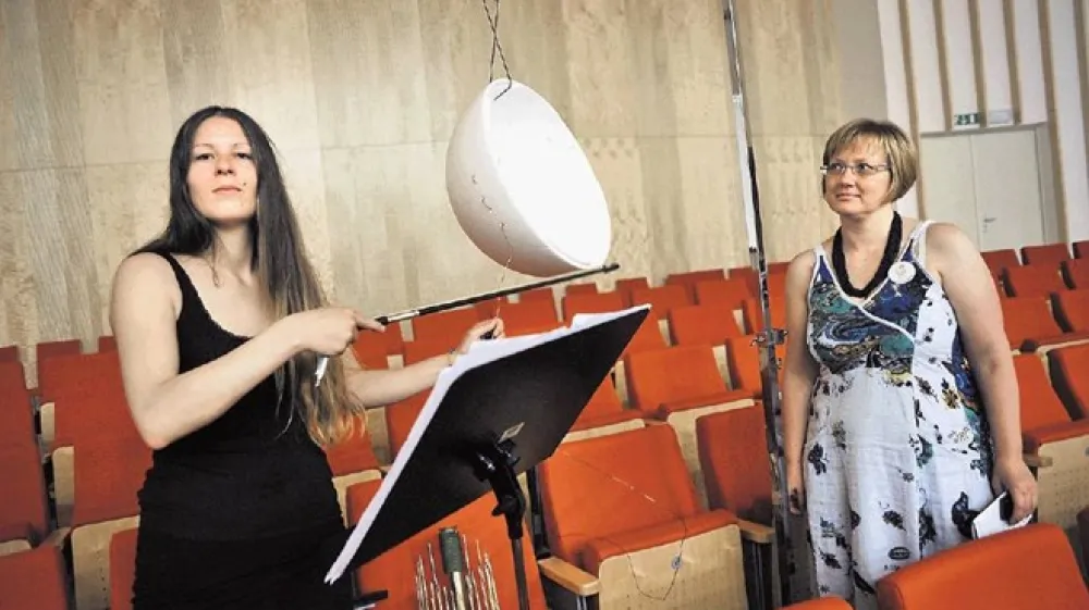 Ročno izdelan tolkalni in&scaron;trument, ki ga je skonstruirala  skladateljica Petra Strahovnik (na fotografiji levo) za svojo  skladbo Med vzhodom in zahodom (Between East and West),  visi s stropa kot luč, po kablu pa se vleče violinski lok.  Skladba je bila izbrana na anonimnem natečaju Festivala  Ljubljana za mednarodni projekt MusMA &ndash; Music Masters on  Air. V Sloveniji smo krstno izvedbo že sli&scaron;ali v okviru leto&scaron;njih  27. slovenskih glasbenih dnevov. Ob skladateljici je Veronika  Brvar, vodja projekta MusMa za Slovenijo in programska  vodja Festivala Ljubljana.