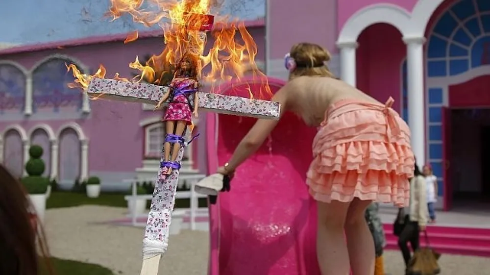 Aktivistka skupine Femen se vzpenja na &raquo;delovno mesto&laquo;, v ospredju njen rekvizit (foto: Reuters)