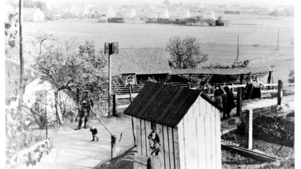 Italijansko-nem&scaron;ki mejni prehod nad Zalokarjevo hi&scaron;o v Ljubljani, kjer je zdaj Cesta Andreja Bitenca.  Fotografija je bila posneta s pobočja proti Ljubljani z vidnimi travniki in njivami v ozadju. Danes je to območje pozidano s stanovanjskimi bloki.