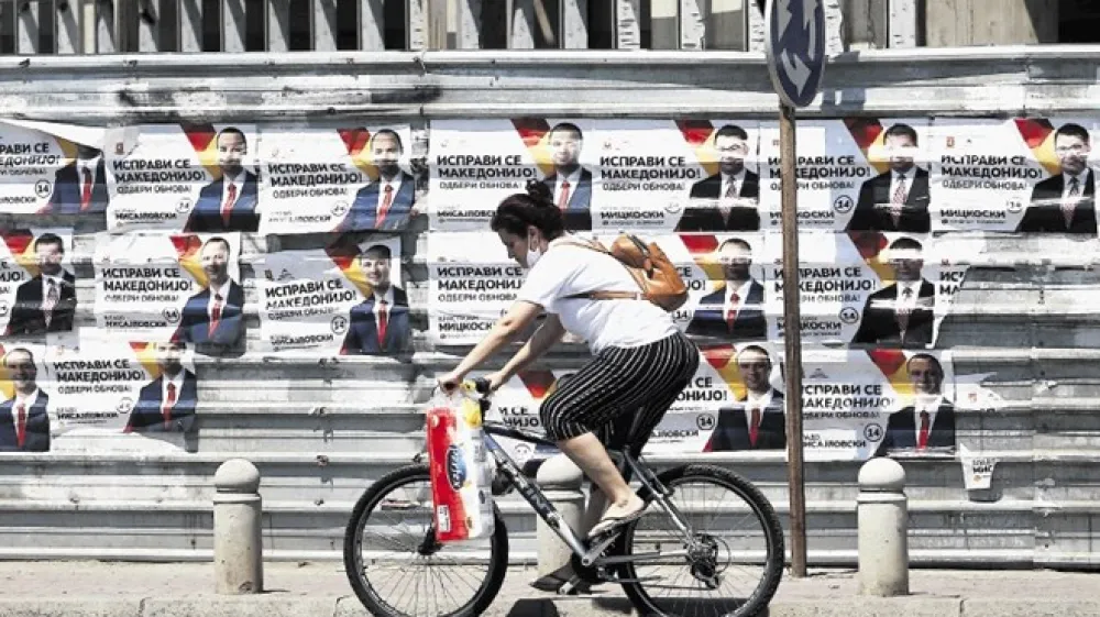 Ženska  se v Skopju  pelje mimo predvolilnih plakatov največje opozicijske stranke VMRO-DPMNE.