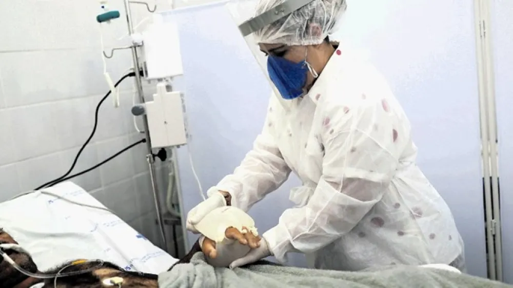 Nekatera zdravila veliko obetajo, a jih bo treba pred množično uporabo v bolni&scaron;nicah &scaron;e temeljito preučiti. Na fotografiji:  sestra v brazilski bolni&scaron;nici bolniku s covidom-19 greje premrle roke z improviziranim termoforjem.