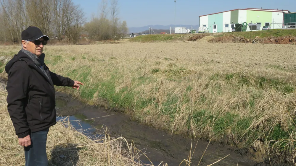 &raquo;Že lani smo začeli opažati, da se v kanalu, tik ob sprehajalni poti po nasipu, nabira blato, ki močno zaudarja,&laquo; pravi Stanko Savnik, predsednik Brodarsko turističnega društva Mostec. V ozadju brežiška čistilna naprava.&nbsp;