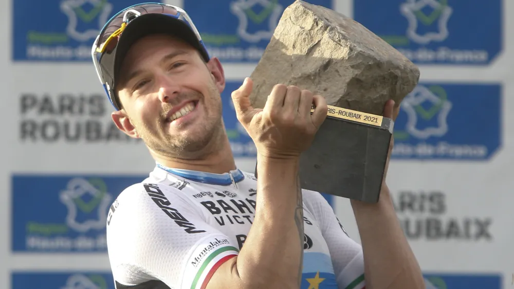 Sonny Colbrelli of Italy lifts the cobblestone trophy after winning the men's Paris Roubaix, a 258 kilometer (160.3 miles) one-day-race cycling race, at the velodrome in Roubaix, northern France, Sunday, Oct. 3, 2021. (AP Photo/Michel Spingler)