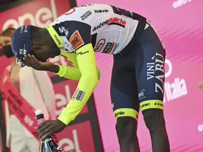 Eritrea's Biniam Girmay touches his eye after spraying sparkling wine on the podium to celebrate winning the 10th stage of the Giro D'Italia cycling race from Pescara to Jesi, Italy, Tuesday, May 17, 2022. Girmay was then taken to a local hospital after getting injured when he popped a champagne cork into his eye during the podium celebration. (Massimo Paolone/LaPresse via AP)