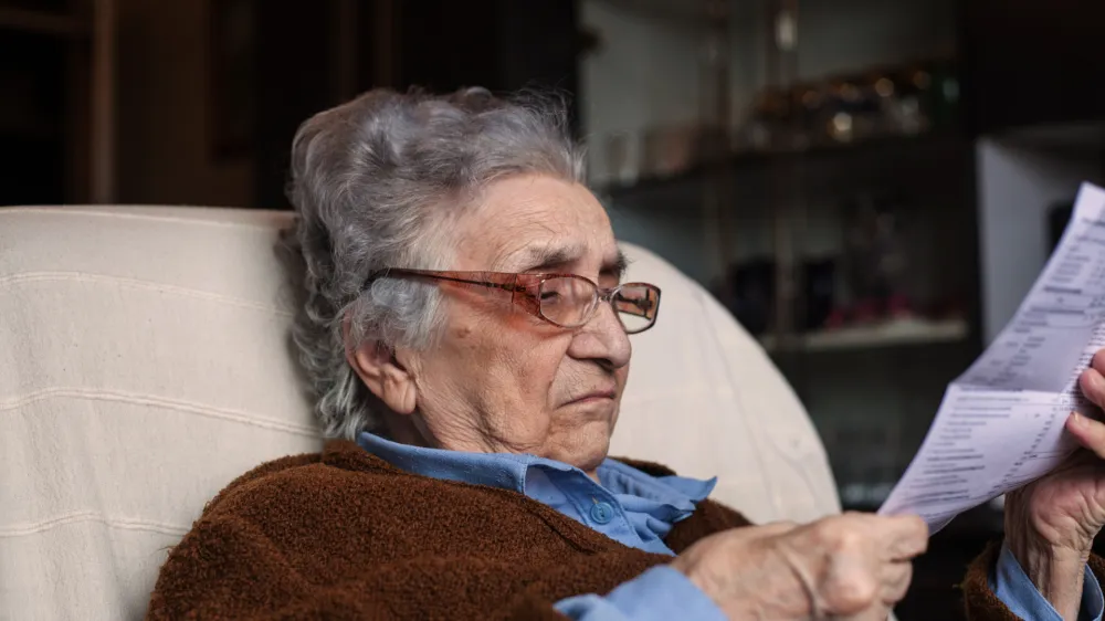 Serious senior woman looking at bills..