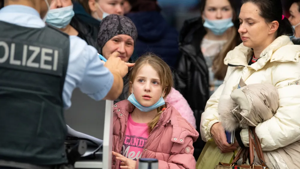 A German police officer speaks to Ukrainian refugees who arrived in Germany with a first refugee plane from Moldova, after fleeing from Russia's invasion of Ukraine, at the international airport of Frankfurt, Germany, March 25, 2022. Boris Roessler/Pool via REUTERS