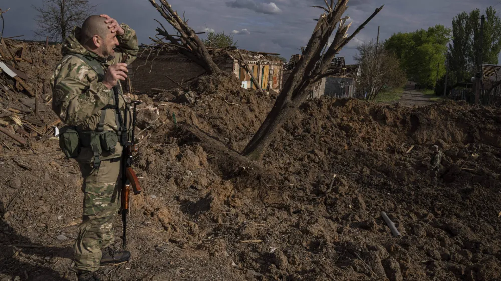 A Ukrainian serviceman inspects a site after an airstrike by Russian forces in Bahmut, Ukraine, Tuesday, May 10, 2022. (AP Photo/Evgeniy Maloletka)