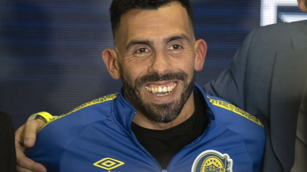 Former Boca Juniors star Carlos Tevez smiles wearing the team´s jersey during his presentation as the new coach for Rosario Central, in Rosario, Argentina, Tuesday, June 21, 2022. (AP Photo/Franco Trovato)