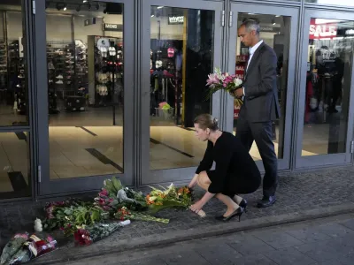 Danish Prime Minister Mette Frederiksen, bottom, and Minister of justice Mattias Tesfaye lay flowers at the entrance of the Field's shopping center in Copenhagen, Denmark, Monday, July 4, 2022. Danish police believe a shopping mall shooting that left three people dead and four others seriously wounded was not terror-related. They said Monday that the gunman acted alone and appears to have selected his victims at random. (AP Photo/Sergei Grits)