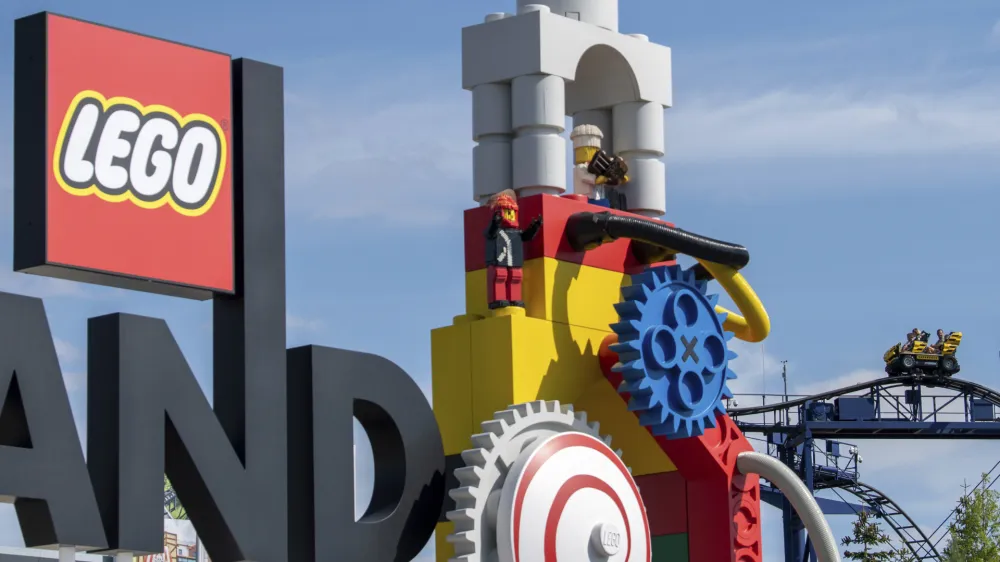 A roller coaster can be seen next to the logo at the entrance to the 'Legoland' amusement park in Guenzburg, southern Germany, Thursday, Aug. 11, 2022. At least 34 people were injured in the accident on a roller coaster at Legoland in Guenzburg, two of them seriously. (Stefan Puchner/dpa via AP)