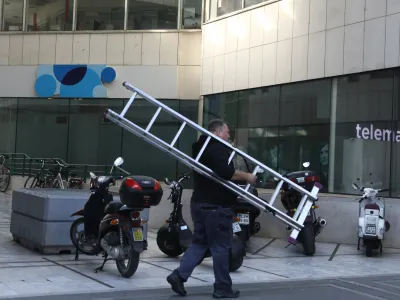  mobilni operater Telemach in Telekom – delavec, lestev, telefoniranje <br><br>- 23.09.2022 - ploščad Trg Ajdovščina pri Metalki v Ljubljani <br> <br>//FOTO: Luka Cjuha