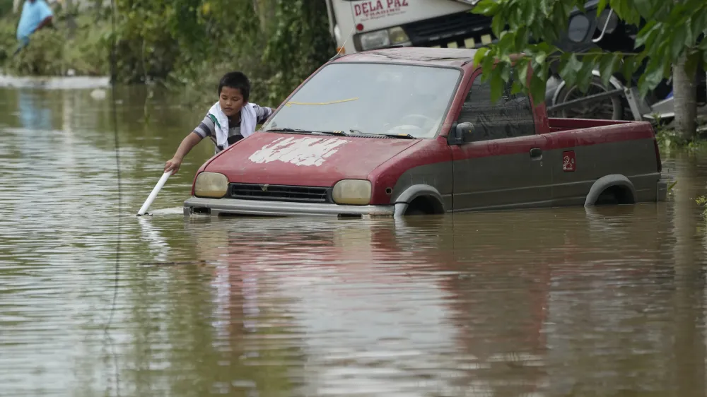 A boy plays along a flooded street from Typhoon Noru in San Miguel town, Bulacan province, Philippines, Monday, Sept. 26, 2022. Typhoon Noru blew out of the northern Philippines on Monday, leaving some people dead, causing floods and power outages and forcing officials to suspend classes and government work in the capital and outlying provinces. (AP Photo/Aaron Favila)