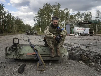 A Ukrainian serviceman smokes a cigarette after he finds and identifies a dead body of a comrade in recently recaptured town of Lyman, Ukraine, Monday, Oct. 3, 2022. (AP Photo/Evgeniy Maloletka)