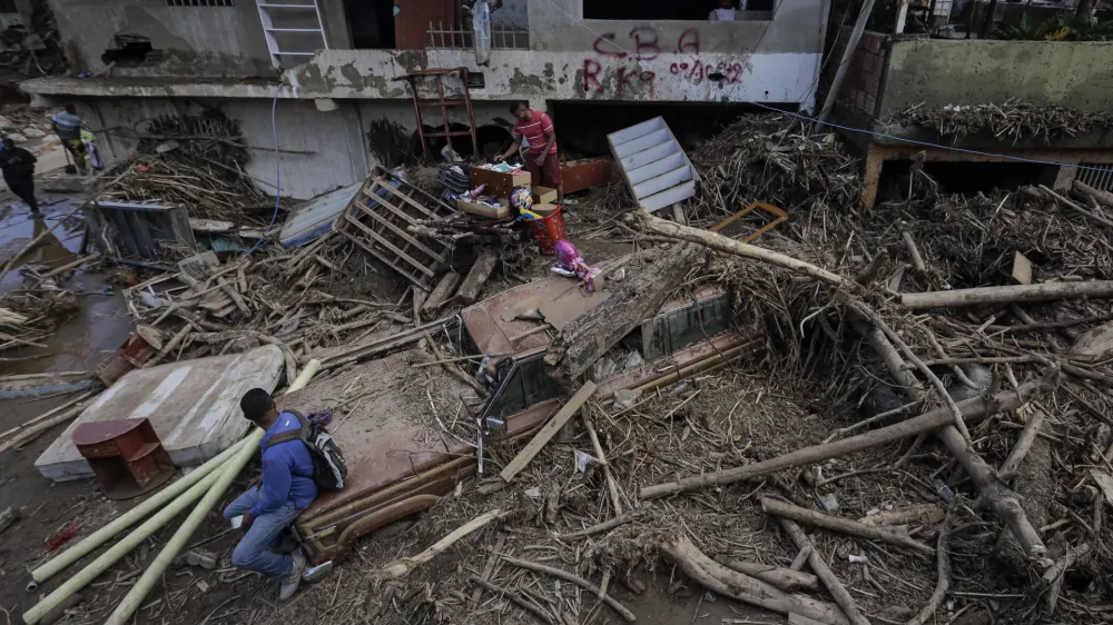 10 October 2022, Venezuela, Las Tejerias: A man sits in the wreckage of a car after floods and a landslide caused by the storm 'Julia'. According to official figures, a total of at least 59 people died in Central and South America as a result of storms and floods. Photo: Jesus Vargas/dpa