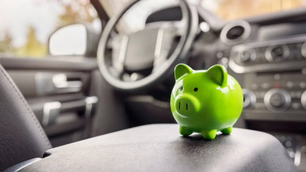 Green piggy bank money box in car interior, vehicle purchase, insurance or driving and motoring cost