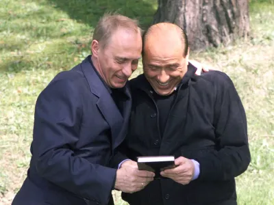 Russian President Vladimir Putin, left, presents Italian Prime Minister Silvio Berlusconi with the book "Berlusconi's Effect," published in Russia, during their informal meeting in the Bocharov Ruchei residence in the Black Sea resort of Sochi, southern Russia, Tuesday, April 2, 2002. Berlusconi, who arrived in Sochi on Tuesday afternoon for his fourth visit with Putin, is the first Western European leader to meet with Putin in his Bocharov Ruchei residence. (AP Photo/ITAR-TASS, Presidential Press Service)