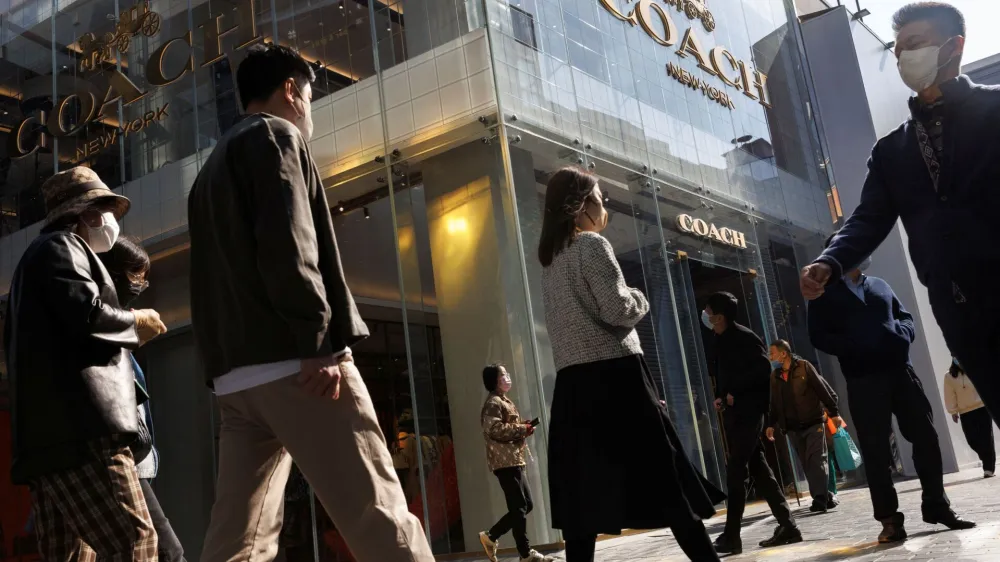 People walk past a store of the Coach luxury fashion retailer in a shopping district in Beijing, China, October 19, 2022. REUTERS/Thomas Peter