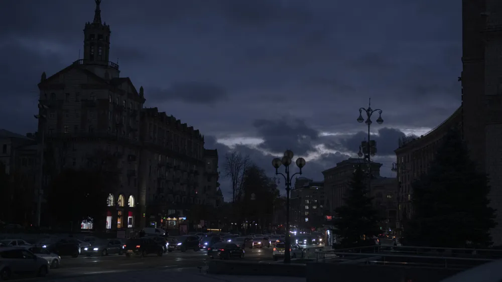 Cars pass at twilight in Kyiv downtown, Ukraine, Monday, Oct. 31, 2022. Rolling blackouts are increasing across Ukraine as the government rushes to stabilise the energy grid and repair the system ahead of winter. (AP Photo/Andrew Kravchenko)