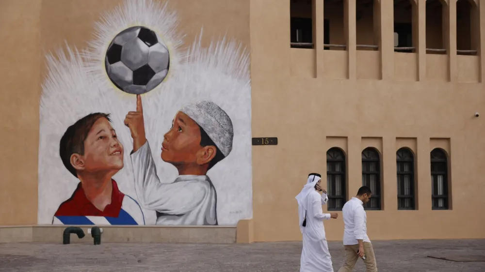Soccer Football - FIFA World Cup Qatar 2022 Preview - Doha, Qatar - November 9, 2022 People walk past a football mural on the walls of Katara Cultural Village ahead of the World Cup REUTERS/John Sibley