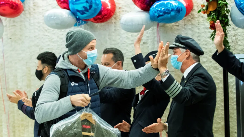 ﻿A man gives a high five to the crew members as he exits baggage claim after landing in the British Airways flight at JFK International Airport in New York, U.S., November 8, 2021. REUTERS/Eduardo Munoz