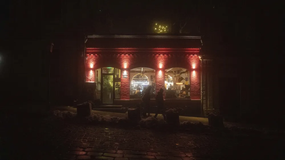 FILE - People walk past a cafe in the city center which lost electrical power after yesterday's Russian rocket attack in Kyiv, Ukraine, Nov. 24, 2022. The hard realities of Ukraine's capital are that a once comfortably livable city of 3 million people is now becoming a tough place to live. But Kyiv has hope, resilience and defiance in abundance. And perhaps more so now than at any time since Russia invaded Ukraine nine months ago. (AP Photo/Evgeniy Maloletka, File)