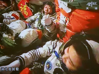 In this image made off the monitor screen at the Beijing Aerospace Flight Control Center and released by China's Xinhua News Agency, China's astronauts Jing Haipeng, center, Liu Wang, left, and Liu Yang sit inside the Shenzhou-9 manned spacecraft while conducting docking with the Tiangong-1 space lab module Monday afternoon, June 18, 2012, 343 kilometers (213 miles) above Earth. (AP Photo/Beijing Aerospace Control Center via Xinhua) NO SALES