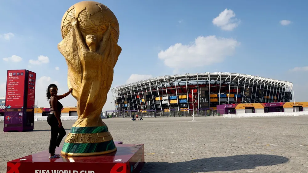Soccer Football - FIFA World Cup Qatar 2022 - 974 Stadium, Doha, Qatar - December 11, 2022 A woman poses with a World Cup replica trophy outside 974 Stadium REUTERS/Bernadett Szabo