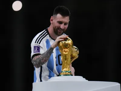 Argentina's Lionel Messi holds best player of the tournament trophy as he touches the World Cup trophy after the World Cup final soccer match between Argentina and France at the Lusail Stadium in Lusail, Qatar, Sunday, Dec. 18, 2022. (AP Photo/Petr David Josek)