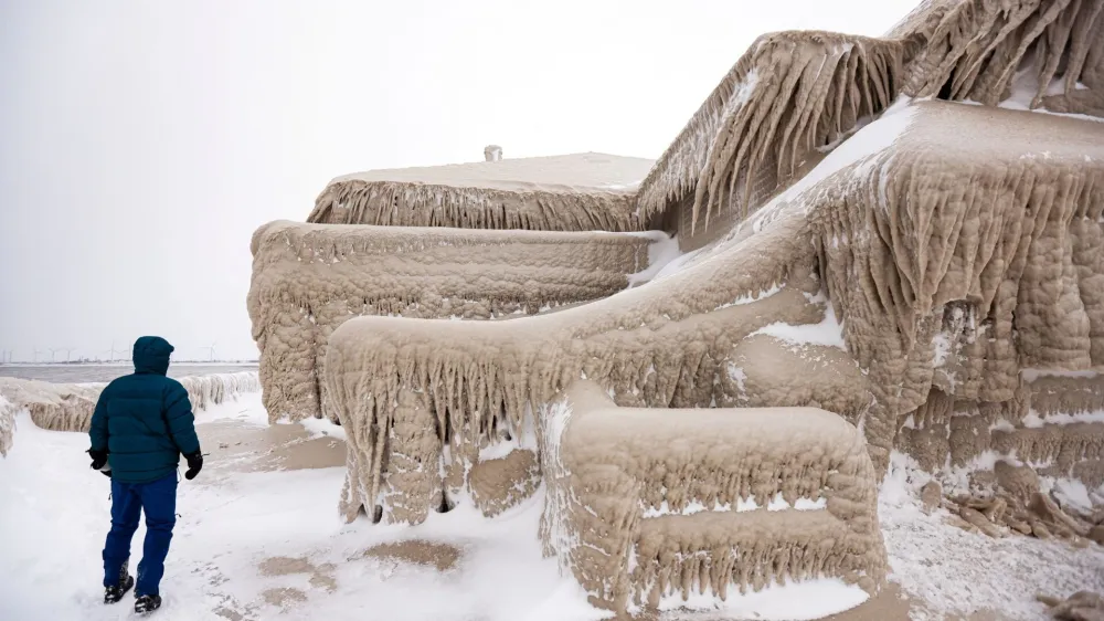 A man walks beside ice formed by the spray of Lake Erie waves which covered a restaurant during a winter storm in Hamburg, New York, U.S., December 26, 2022. REUTERS/Lindsey DeDario   TPX IMAGES OF THE DAY