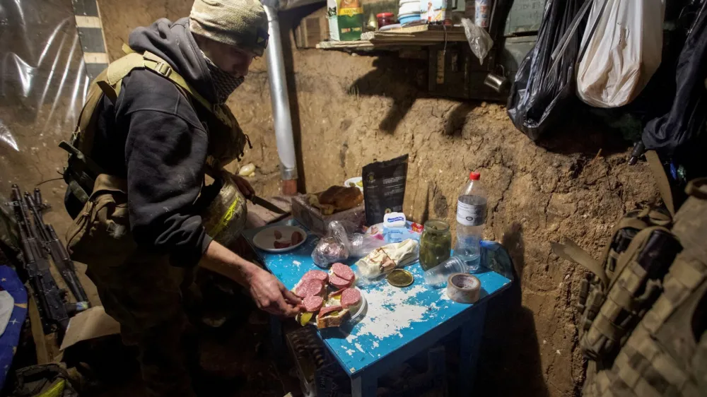 A Ukrainian service member prepares food in a shelter near their position at a frontline, amid Russia's attack on Ukraine, in Donetsk region, Ukraine January 1, 2023. REUTERS/Anna Kudriavtseva