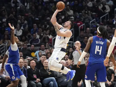 Dallas Mavericks guard Luka Doncic, center, shoots as Los Angeles Clippers forward Norman Powell, left, and guard Terance Mann defend during the second half of an NBA basketball game Tuesday, Jan. 10, 2023, in Los Angeles. (AP Photo/Mark J. Terrill)