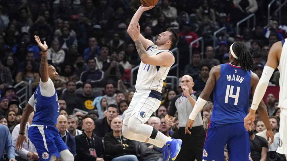 Dallas Mavericks guard Luka Doncic, center, shoots as Los Angeles Clippers forward Norman Powell, left, and guard Terance Mann defend during the second half of an NBA basketball game Tuesday, Jan. 10, 2023, in Los Angeles. (AP Photo/Mark J. Terrill)