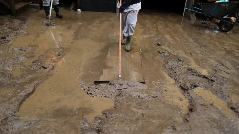 Neighbors clean a driveway after the San Lorenzo river flooded Felton Grove, California, U.S., January 14, 2023. REUTERS/David Swanson