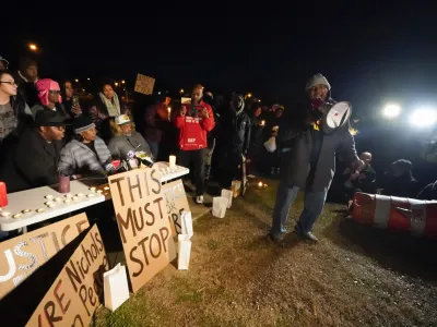 Rev. Andre E Johnson, of the Gifts of Life Ministries, preaches at a candlelight vigil for Tyre Nichols, who died after being beaten by Memphis police officers, in Memphis, Tenn., Thursday, Jan. 26, 2023. Behind him, seated center, are Tyre's mother RowVaughn Wells and his stepfather Rodney Wells. (AP Photo/Gerald Herbert)
