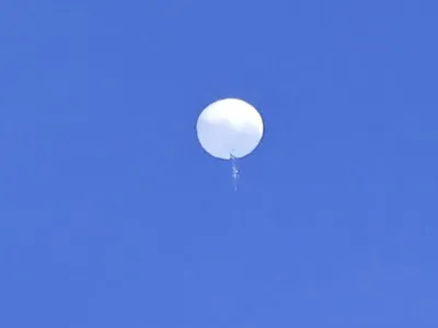 In this photo provided by Travis Huffstetler Photography, a large balloon drifts above the Atlantic Ocean, just off the coast of the Carolinas, Saturday, Feb. 4, 2023. The massive white orb that drifted across U.S. airspace this week and was shot down by the Air Force over the Atlantic on live television Saturday triggered a diplomatic maelstrom and blew up on social media. (Travis Huffstetler Photography via AP)
