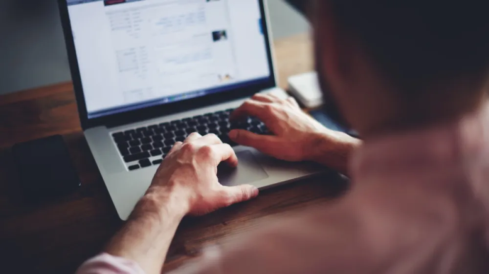 Cropped image of a young man working on his laptop in a coffee shop, rear view of business man hands busy using laptop at office desk, young male student typing on computer sitting at wooden table