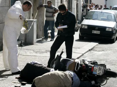 Police forensic experts search for evidence near the lifeless bodies of Angelo Scoppetta and Carlo Balzamo killed in a Camorra-style ambush in Torre Annunziata, near Naples, Wednesday, Sept. 29 2004. The Camorra run extortion rackets, illegal gambling, drug and arms trafficking in the Naples area. (AP Photo/Salvatore Laporta)