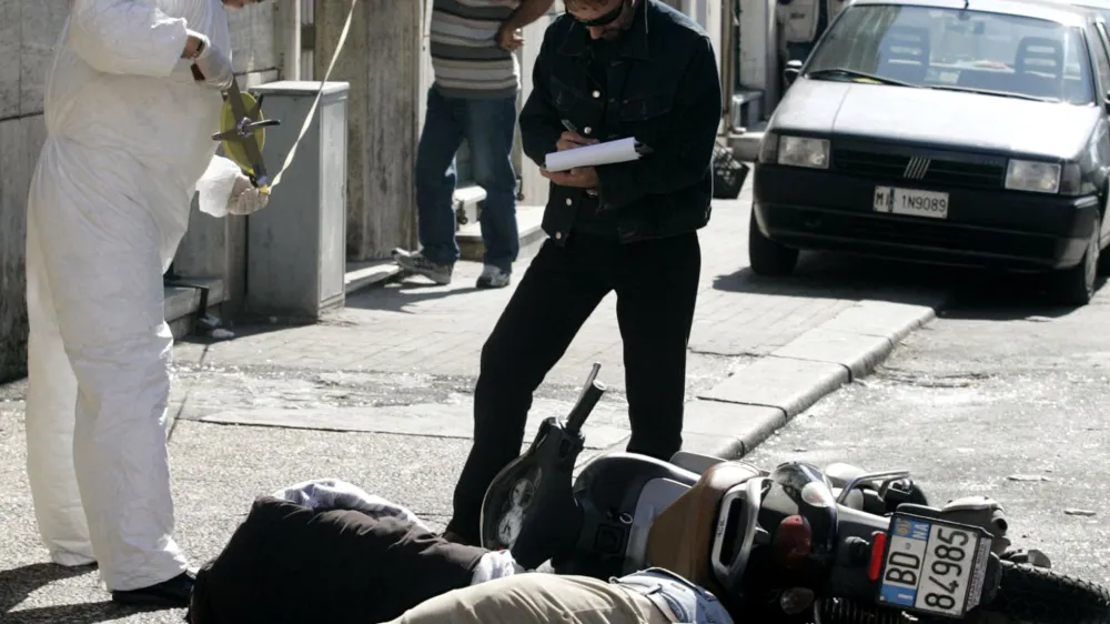 Police forensic experts search for evidence near the lifeless bodies of Angelo Scoppetta and Carlo Balzamo killed in a Camorra-style ambush in Torre Annunziata, near Naples, Wednesday, Sept. 29 2004. The Camorra run extortion rackets, illegal gambling, drug and arms trafficking in the Naples area. (AP Photo/Salvatore Laporta)