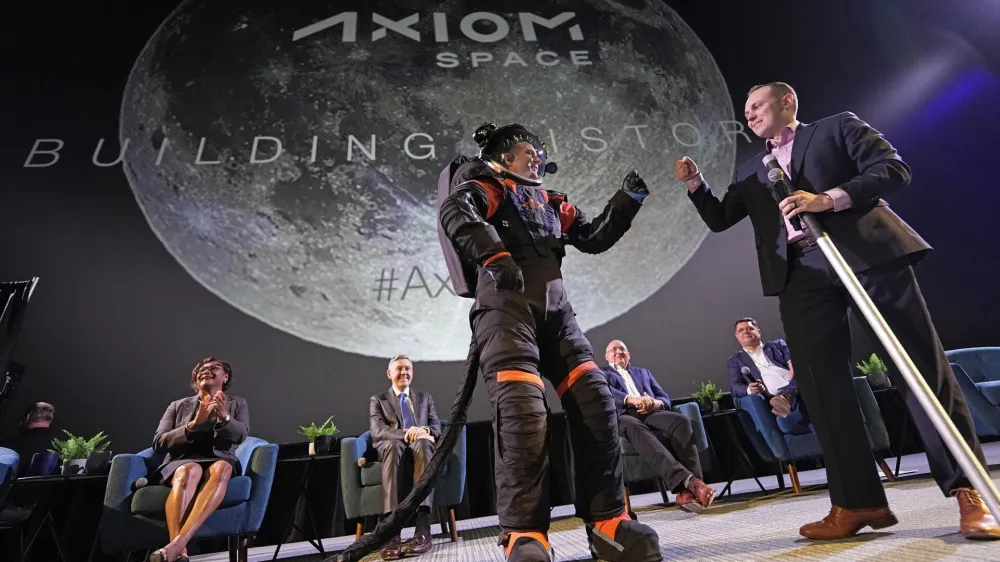 CORRECTS ID AT RIGHT TO RUSSELL RALSTON, NOT MARK GREELEY - Axiom Space chief engineer Jim Stein, left, bumps fists with deputy manager for extravehicular activity Russell Ralston while demonstrating a prototype spacesuit, Wednesday, March 15, 2023, in Houston. NASA selected Axiom Space to design the spacesuits that its moonwalking astronauts will wear when they step onto the lunar surface later this decade. (AP Photo/David J. Phillip)