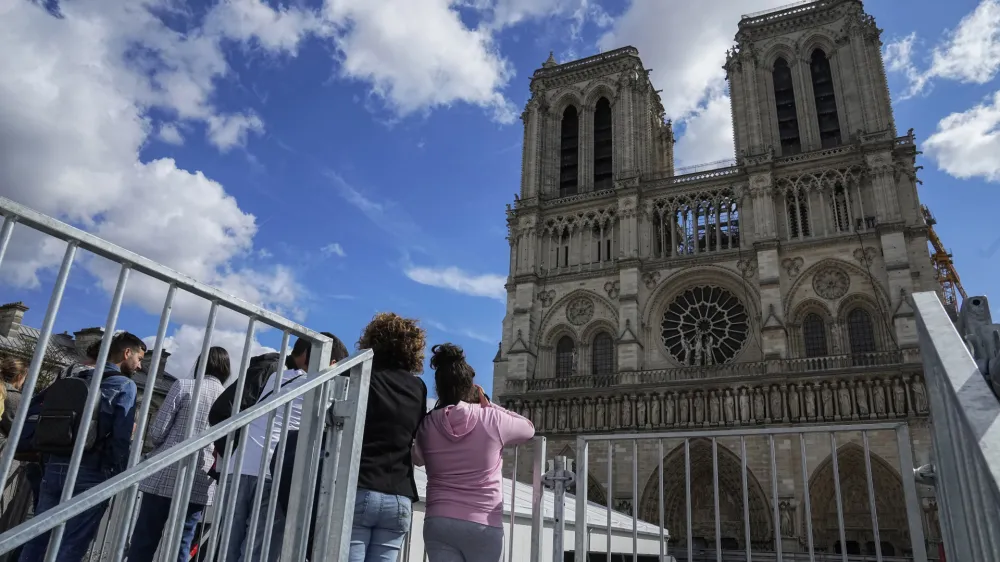 FILE - People have a close look of Notre Dame cathedral as they visit the rebuilding site during Heritage Day in Paris, Saturday, Sept. 17, 2022. France's Notre Dame Cathedral's reconstruction is progressing enough to allow its reopening to visitors and masses at the end of next year, less than six years after the after the shocking fire that tore through its roof, French officials said as an exhibit pays tribute to hundreds of artisans working on it. (AP Photo/Michel Euler, File)