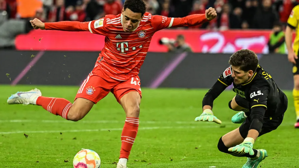 01 April 2023, Bavaria, Munich: Bayern's Jamal Musiala and Dortmund's goalkeeper Gregor Kobel in a duel during the German Bundesliga soccer match between FC Bayern Munich and Borussia Dortmund at Allianz Arena. Photo: Sven Hoppe/dpa - IMPORTANT NOTICE: DFL and DFB regulations prohibit any use of photographs as image sequences and/or quasi-video.